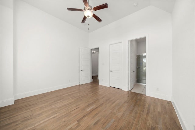 unfurnished bedroom featuring hardwood / wood-style floors, ceiling fan, high vaulted ceiling, and ensuite bath