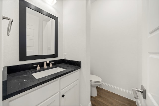 bathroom with toilet, vanity, and hardwood / wood-style flooring