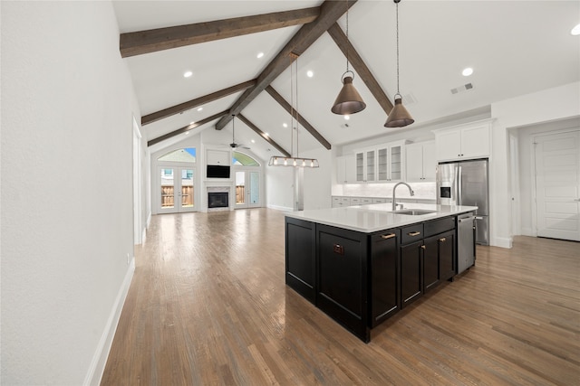 kitchen featuring a kitchen island with sink, hanging light fixtures, ceiling fan, beamed ceiling, and white cabinetry