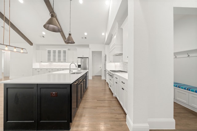 kitchen with decorative light fixtures, white cabinetry, backsplash, and a large island with sink