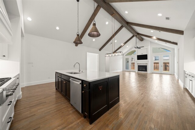 kitchen featuring dishwasher, sink, beamed ceiling, pendant lighting, and a center island with sink