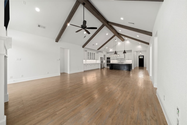 unfurnished living room featuring ceiling fan, beamed ceiling, high vaulted ceiling, and dark wood-type flooring