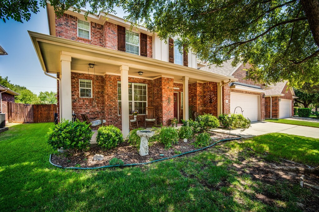 view of front facade featuring a porch, a garage, central air condition unit, and a front yard