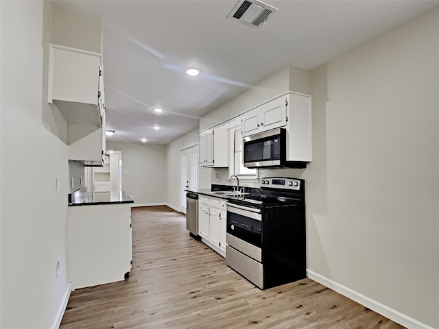 kitchen with appliances with stainless steel finishes, light wood-type flooring, sink, and white cabinetry