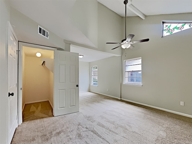 unfurnished bedroom featuring beamed ceiling, ceiling fan, light carpet, and high vaulted ceiling