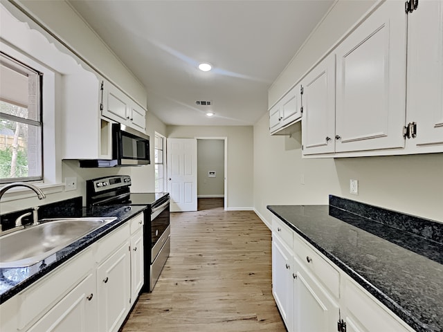 kitchen featuring white cabinets, sink, stainless steel appliances, dark stone countertops, and light wood-type flooring