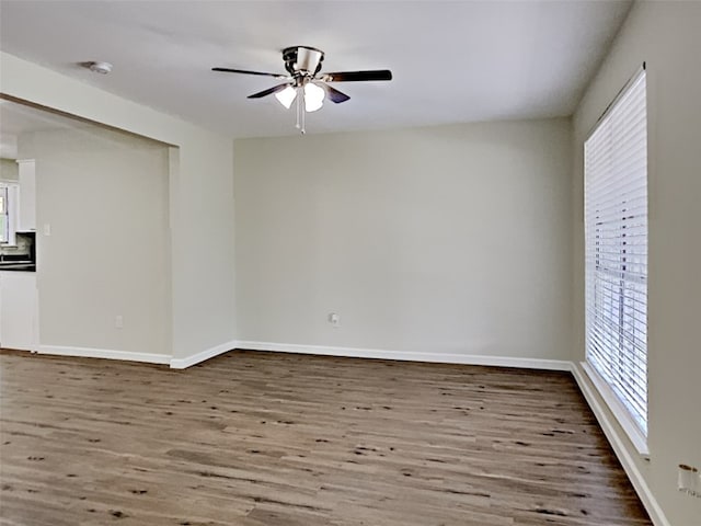 unfurnished room featuring plenty of natural light, wood finished floors, and ceiling fan