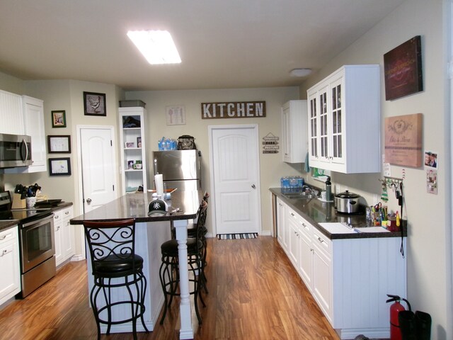 kitchen featuring a kitchen island, stainless steel appliances, white cabinets, and dark hardwood / wood-style floors