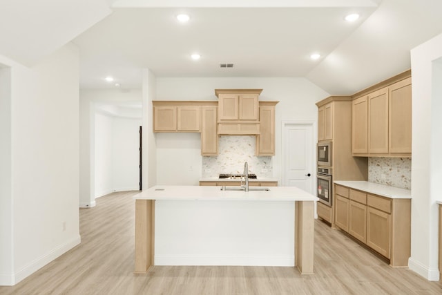 kitchen featuring sink, light hardwood / wood-style flooring, light brown cabinets, appliances with stainless steel finishes, and an island with sink