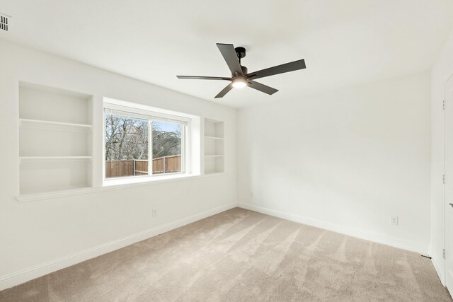 unfurnished room with carpet floors, built in features, and ceiling fan