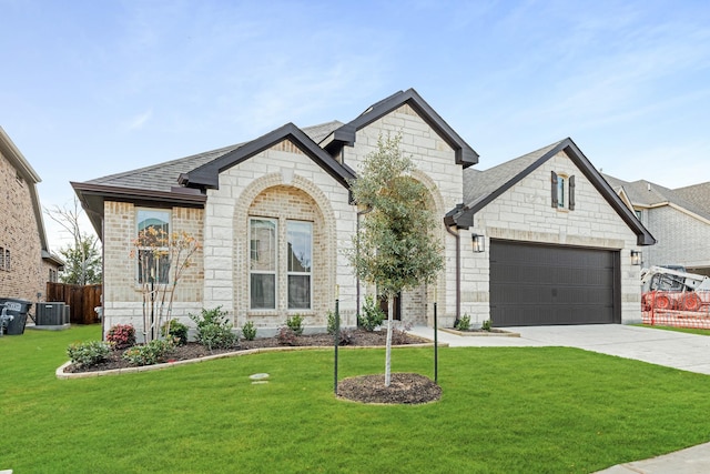 view of front facade with a garage, central air condition unit, and a front lawn