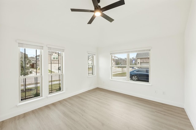 empty room with ceiling fan, vaulted ceiling, and light hardwood / wood-style floors