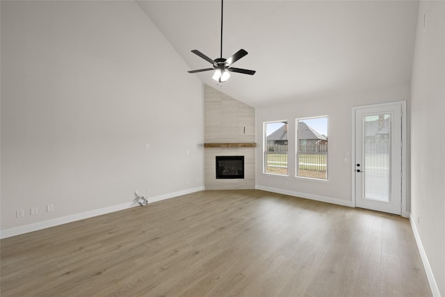 unfurnished living room with baseboards, light wood-type flooring, a fireplace, high vaulted ceiling, and a ceiling fan