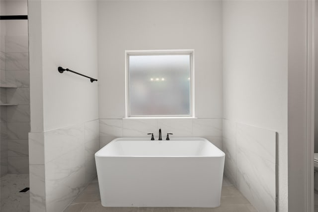 full bathroom featuring a tile shower, a soaking tub, toilet, and tile walls