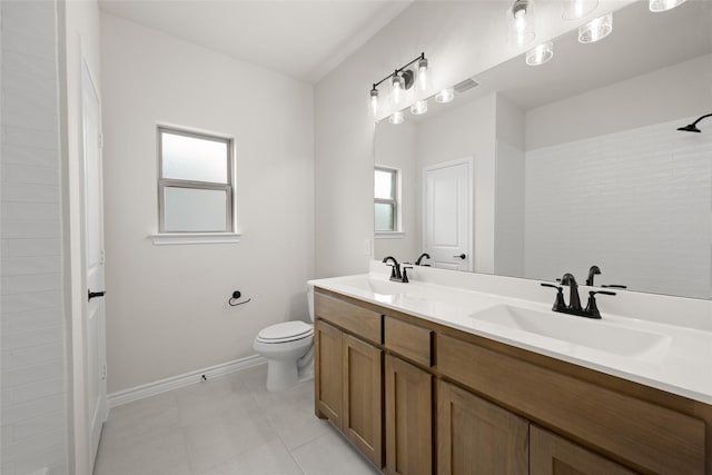 bathroom with tile patterned floors, toilet, a sink, double vanity, and baseboards