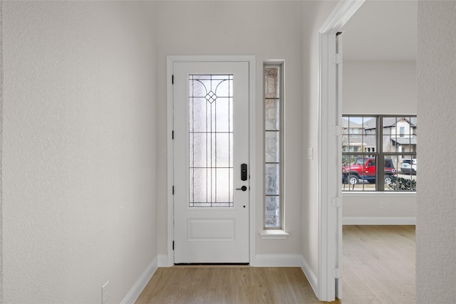 doorway featuring baseboards and wood finished floors