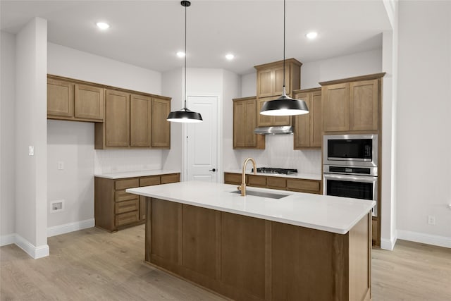 kitchen with a sink, stainless steel appliances, decorative backsplash, and light wood finished floors