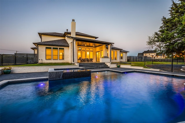 pool at dusk with an in ground hot tub and a patio