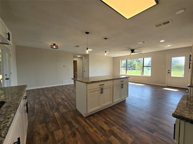 kitchen featuring pendant lighting, stone countertops, white cabinets, and a center island