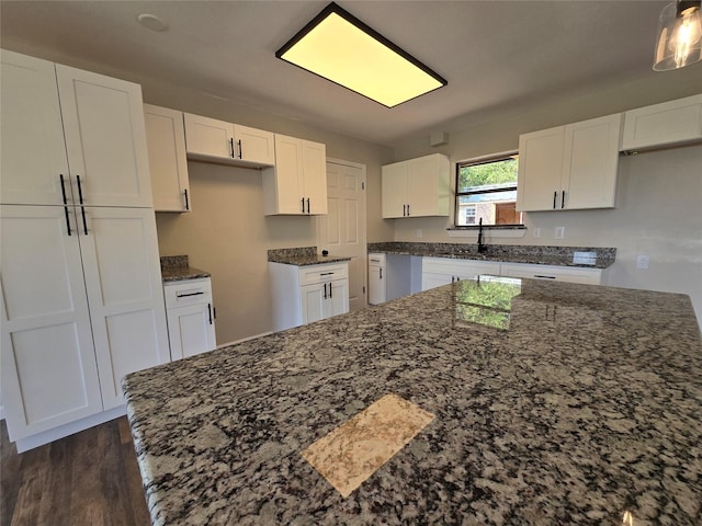 kitchen featuring dark hardwood / wood-style flooring, white cabinets, dark stone counters, and sink