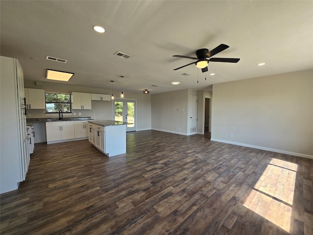 kitchen with a kitchen island, decorative light fixtures, white cabinetry, dark hardwood / wood-style flooring, and sink