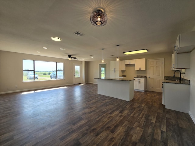 kitchen with pendant lighting, a kitchen island, white cabinetry, dark hardwood / wood-style floors, and ceiling fan