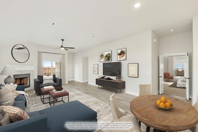 living room with a premium fireplace, ceiling fan, and light hardwood / wood-style floors