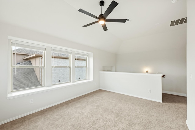 interior space featuring ceiling fan, vaulted ceiling, and light carpet