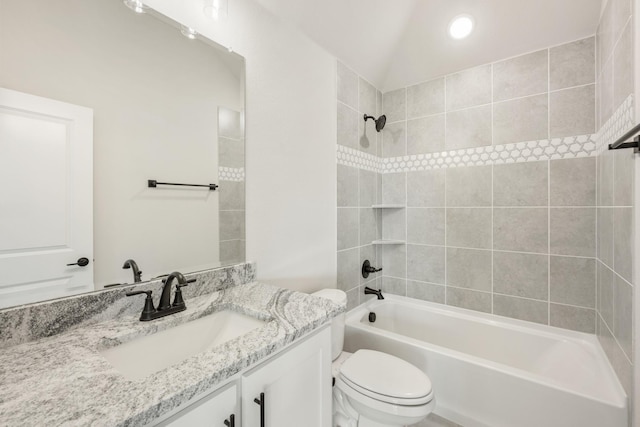 full bathroom with tiled shower / bath, lofted ceiling, vanity, and toilet