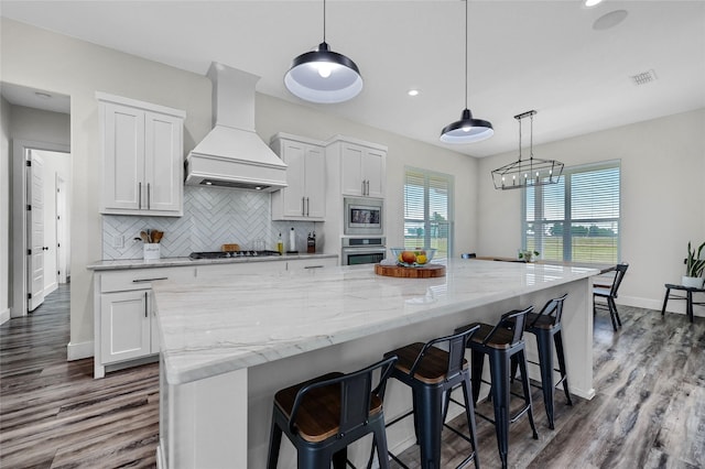 kitchen featuring appliances with stainless steel finishes, white cabinetry, visible vents, and custom range hood