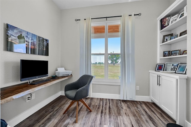 office space featuring baseboards, dark wood-style flooring, and built in study area