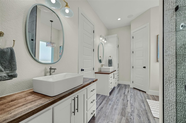 bathroom with wood finished floors, two vanities, a sink, and baseboards