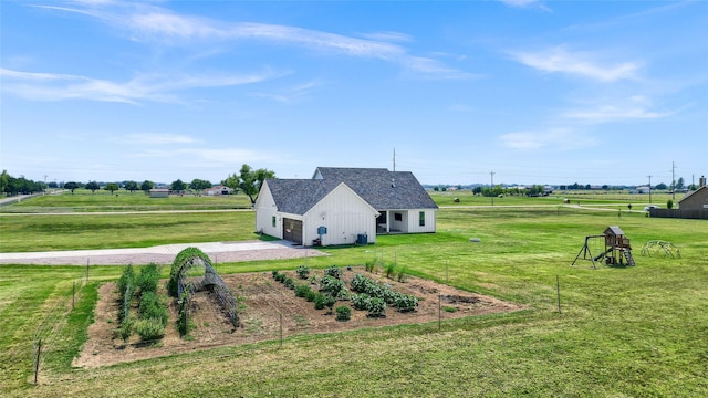 view of property exterior featuring an outbuilding, roof with shingles, a lawn, fence, and a rural view