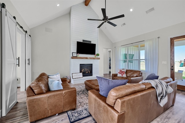 living room featuring a barn door, light wood-style flooring, and visible vents