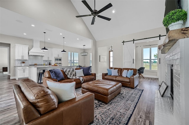 living area with light wood-style floors, a barn door, high vaulted ceiling, and a wealth of natural light