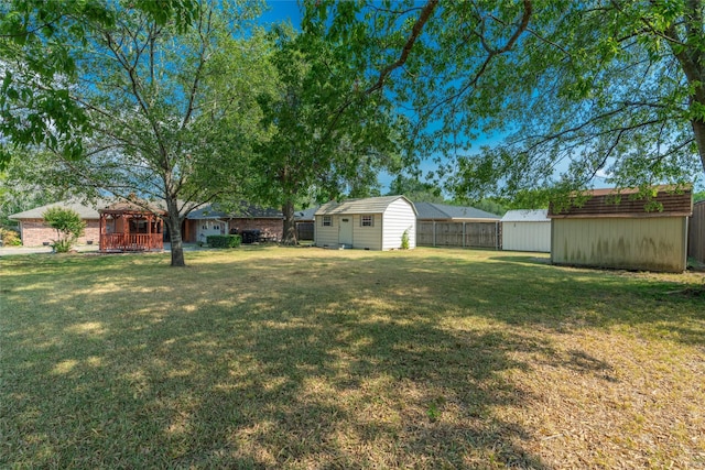 view of yard featuring a storage unit, an outdoor structure, and fence