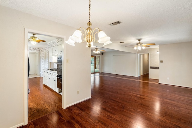 unfurnished room featuring a textured ceiling, ceiling fan with notable chandelier, dark wood-type flooring, visible vents, and baseboards