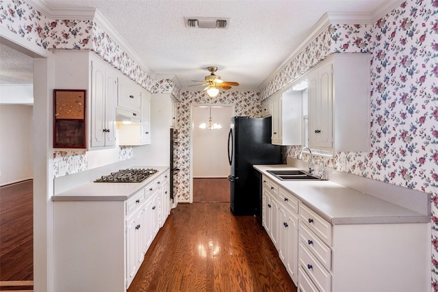 kitchen featuring a sink, a textured ceiling, gas cooktop, and wallpapered walls