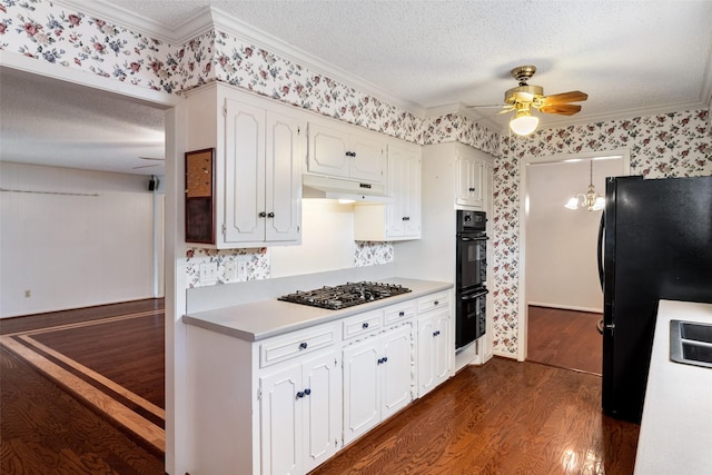 kitchen featuring black appliances, under cabinet range hood, a textured ceiling, and wallpapered walls