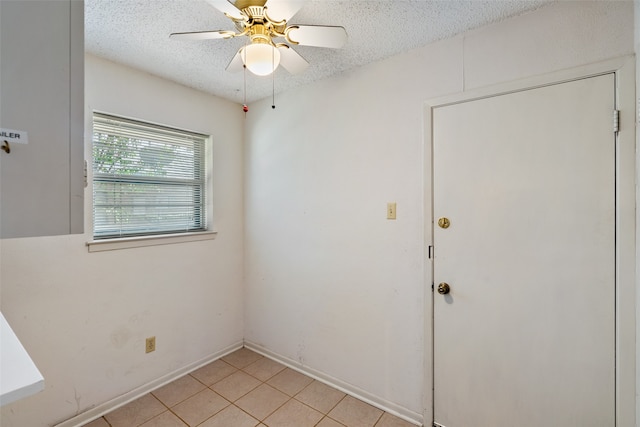 empty room with a textured ceiling, ceiling fan, and light tile patterned floors