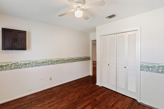 unfurnished bedroom featuring ceiling fan, dark wood-type flooring, a closet, and a textured ceiling