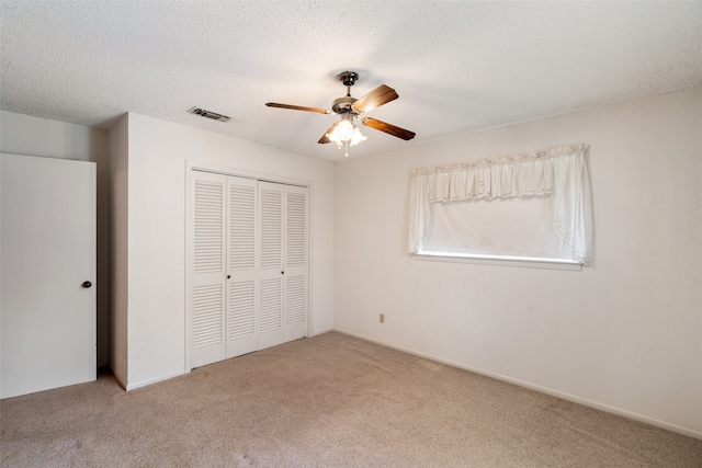 unfurnished bedroom with ceiling fan, a closet, light carpet, and a textured ceiling