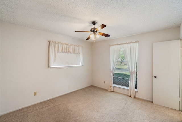 empty room featuring ceiling fan, light carpet, and a textured ceiling