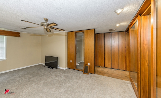 unfurnished bedroom featuring ceiling fan, a textured ceiling, and light carpet