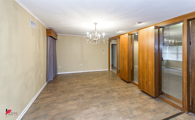 spare room with an inviting chandelier, hardwood / wood-style flooring, and ornamental molding