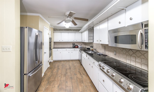 kitchen featuring dark wood-type flooring, white cabinetry, appliances with stainless steel finishes, crown molding, and ceiling fan