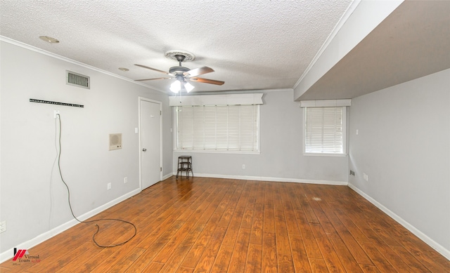 empty room featuring ceiling fan, a textured ceiling, crown molding, and dark wood-type flooring