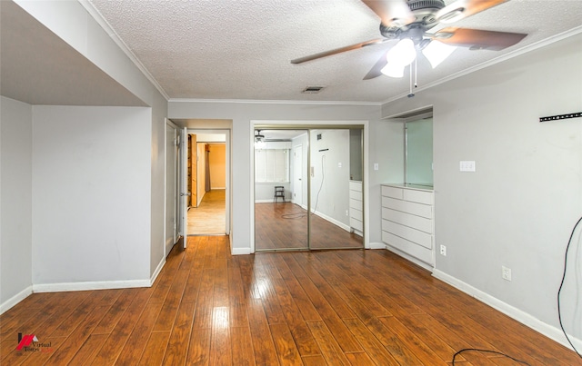 unfurnished bedroom with a closet, a textured ceiling, crown molding, ceiling fan, and dark hardwood / wood-style floors