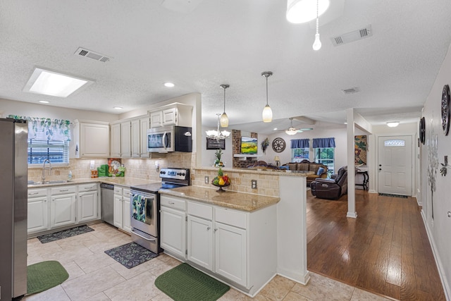 kitchen with sink, kitchen peninsula, light hardwood / wood-style flooring, and stainless steel appliances