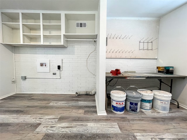 laundry room with hookup for a washing machine, wood-type flooring, and brick wall